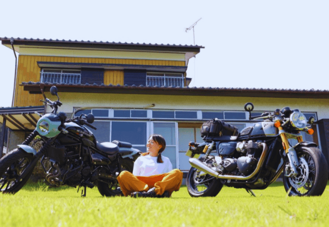 古民家の前でバイクを見つめる女性